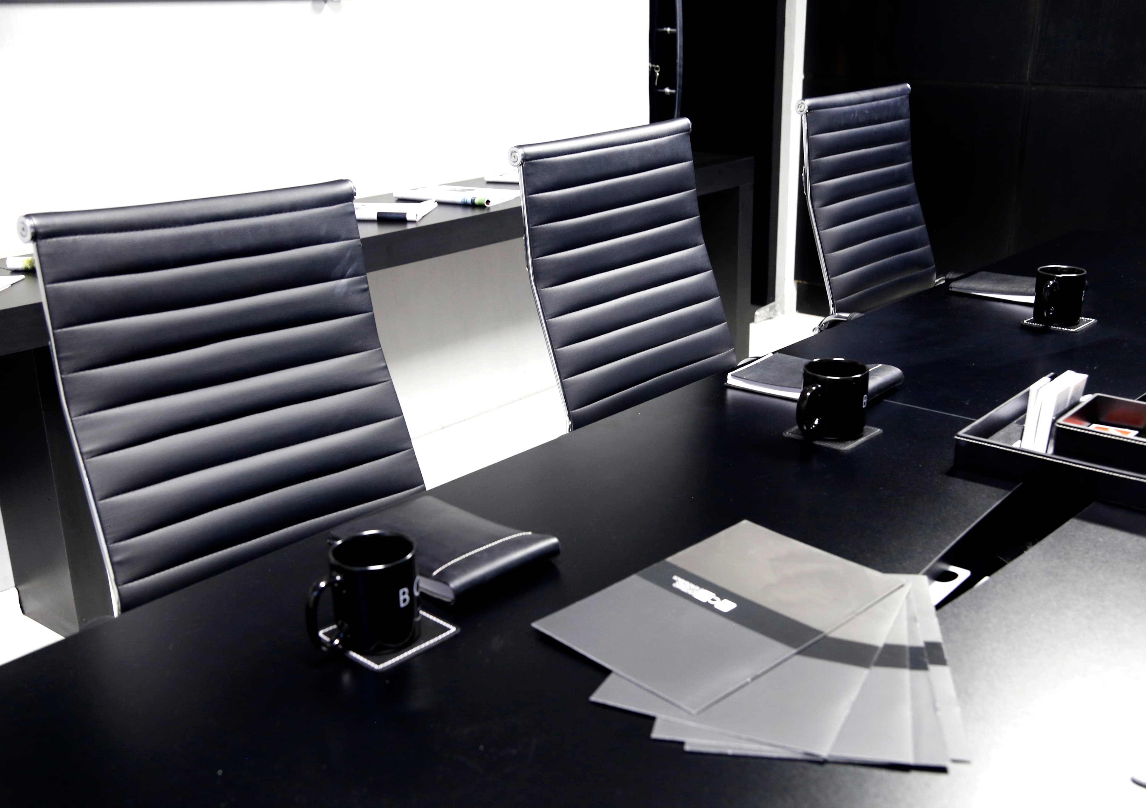 Detalhe da mesa de reunião executiva com cadeiras e material corporativo